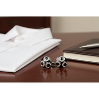 Black and silver cufflinks with circular design on a white background