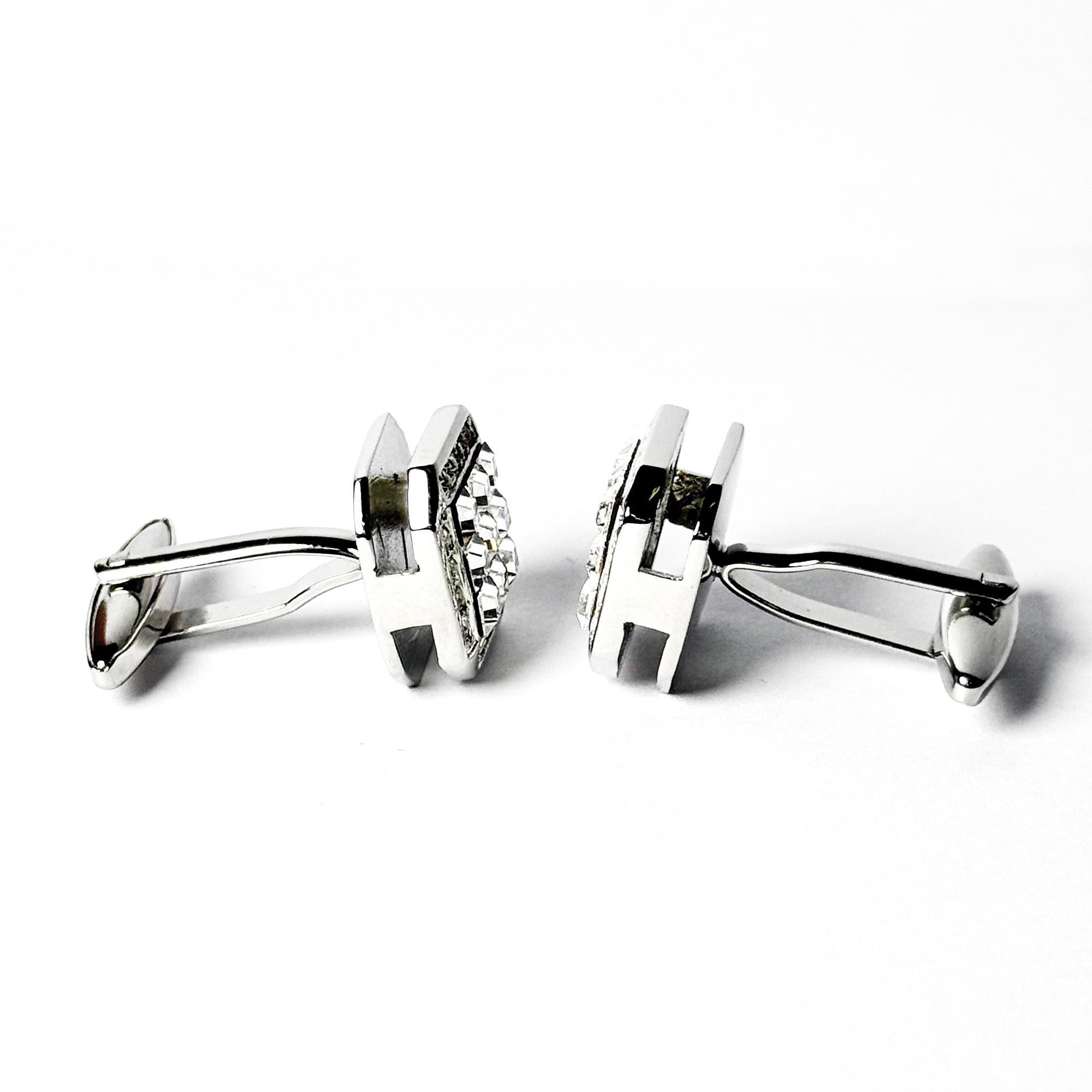 Pair of silver cufflinks with a clear gemstone on a white background
