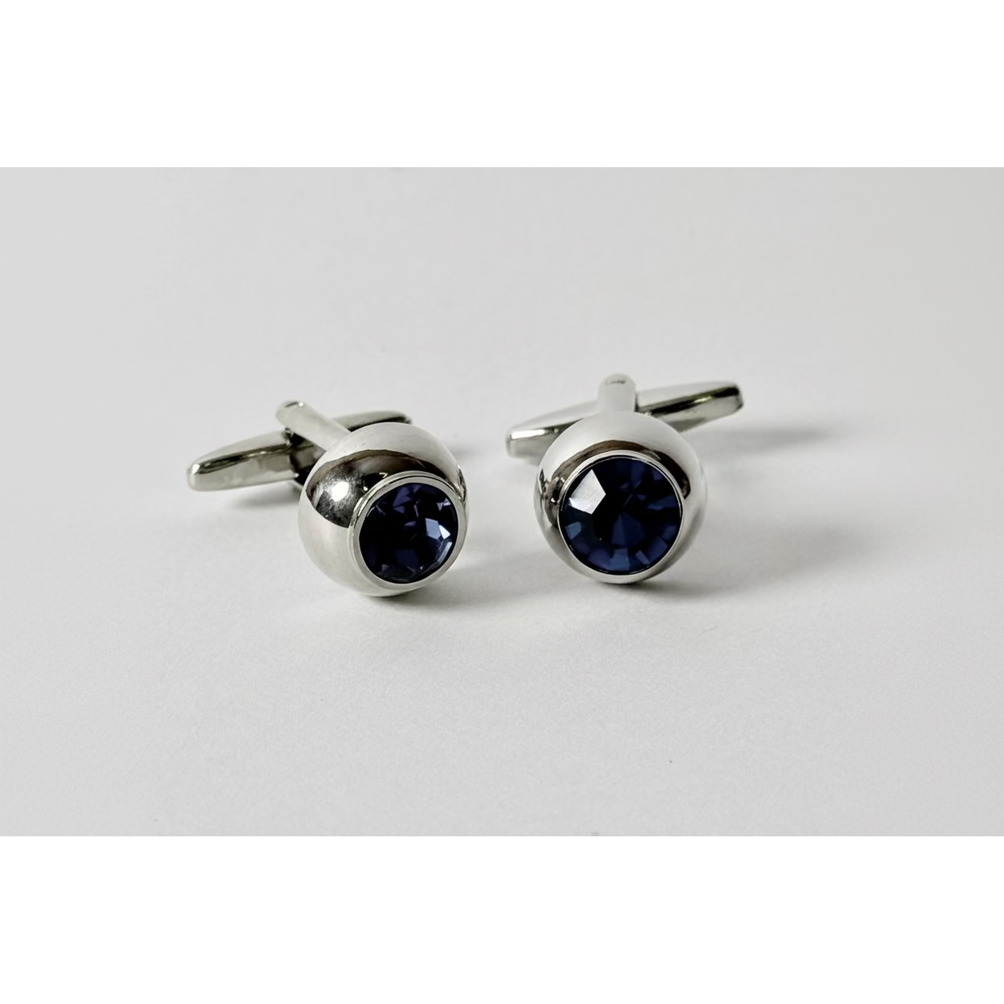 Pair of silver cufflinks with blue gemstones on a light gray background