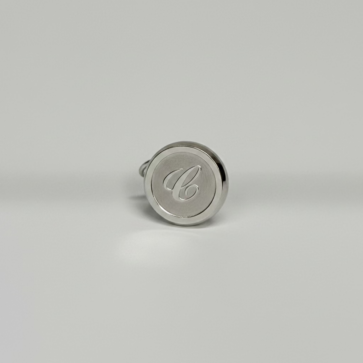 Silver pendant with a monogram on a light gray background