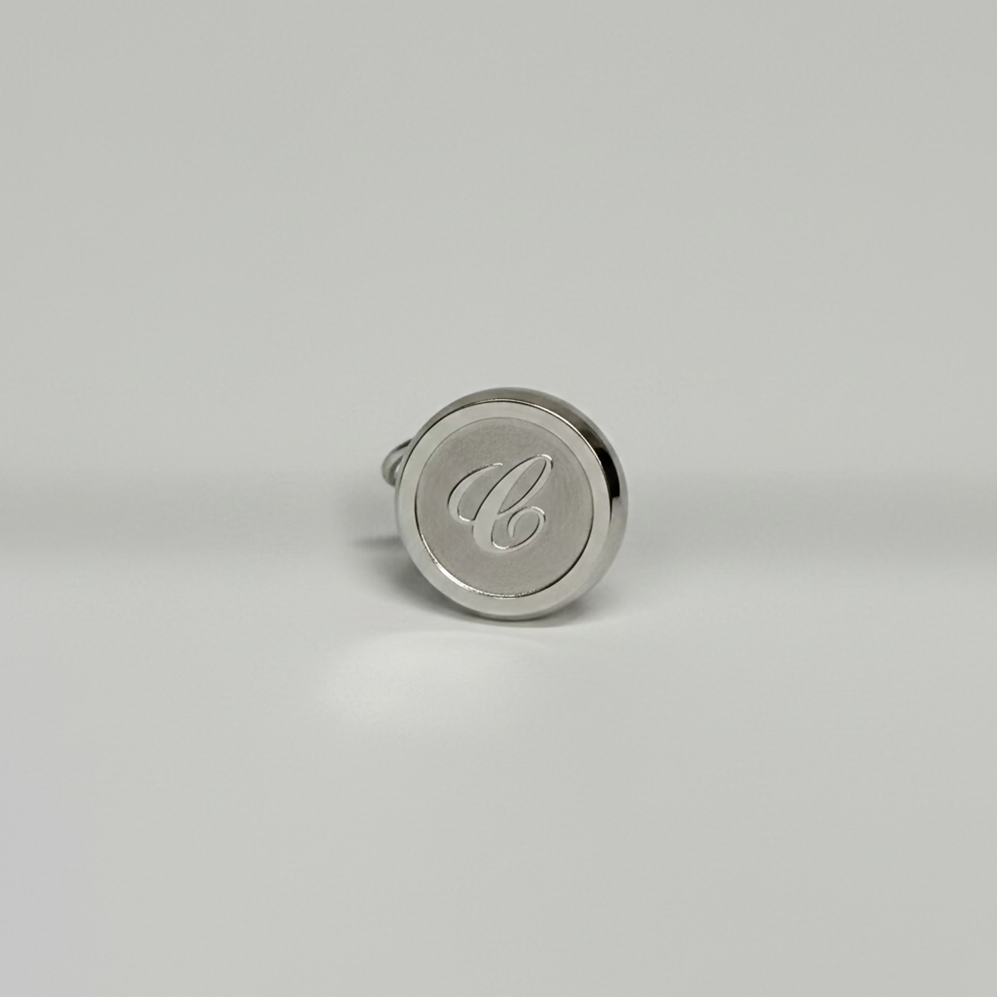 Silver pendant with a monogram on a light gray background