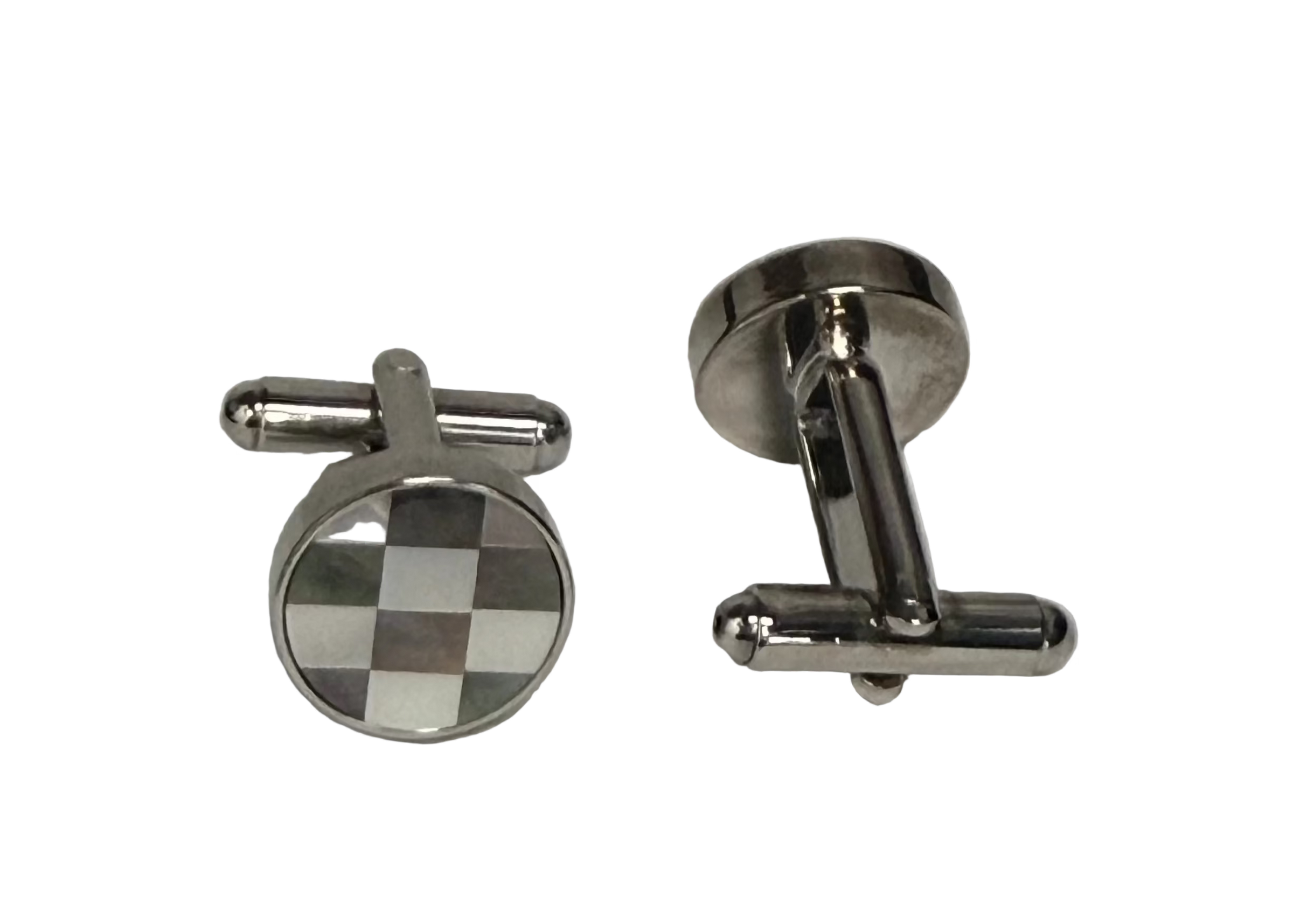 A pair of silver-toned metal cufflinks on a Plan background. One cufflink is shown from the front, featuring a round face with a black and white checkered pattern, and the other is shown from the side/back, displaying its polished silver-toned metal construction.