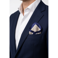 A close-up of a navy blue suit jacket worn by a model, paired with a white dress shirt and a patterned navy and beige pocket square in the breast pocket.