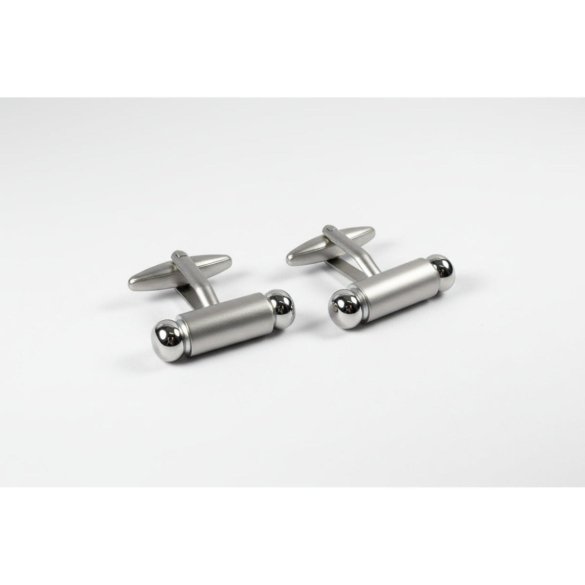 Silver cylindrical cufflinks on a white background