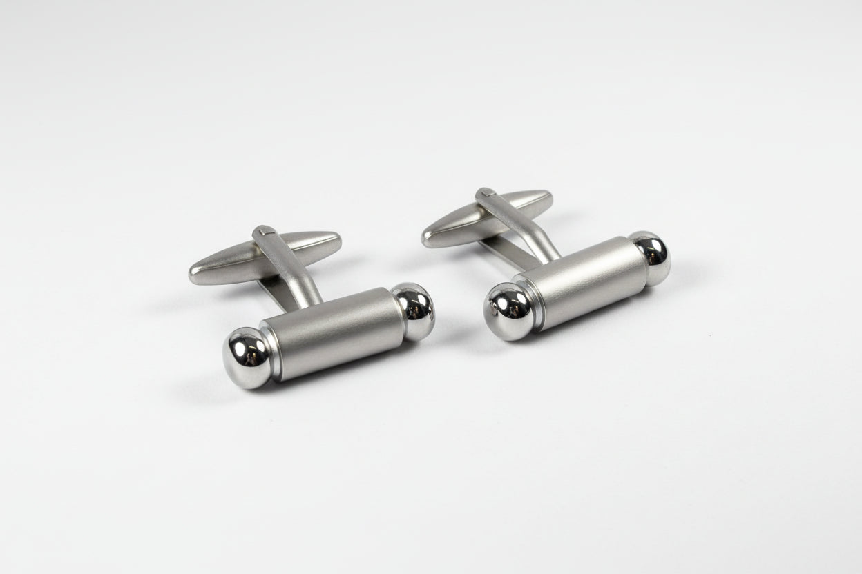 Silver cylindrical cufflinks on a white background