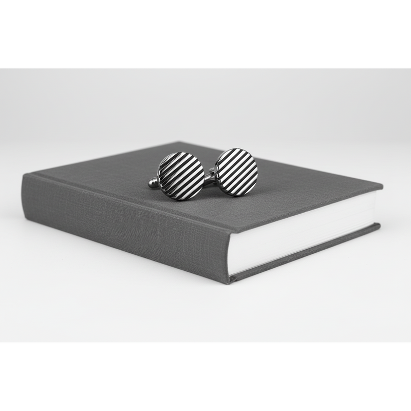 Black horizontal stripe cufflinks on a grey book, showcasing a modern design for formal attire.